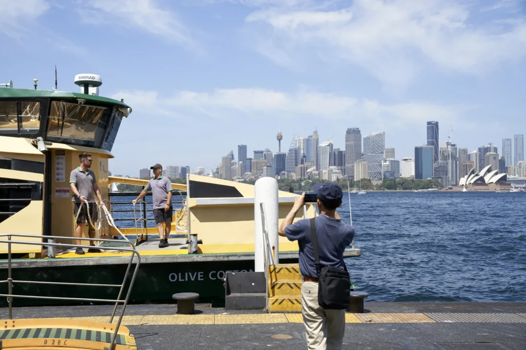 Man watching a ferry at Circular Quay near Quay Quarter Tower in Sydney