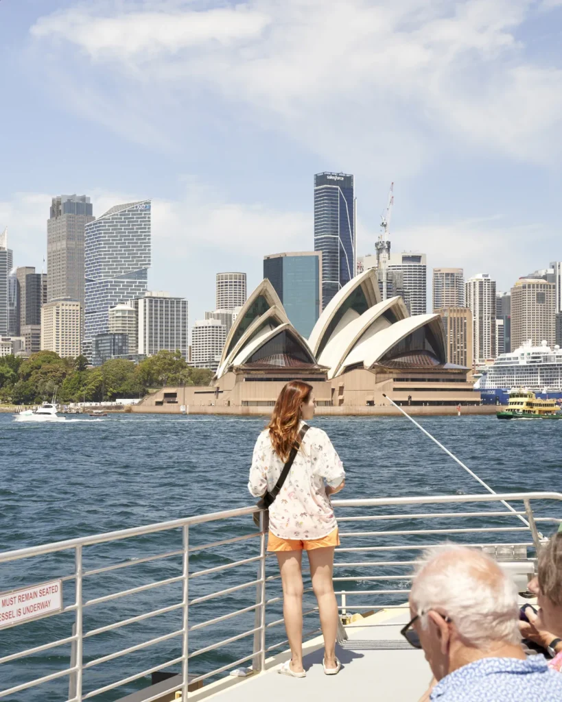 Sydney Opera House from ferry with Quay Quarter Tower visible in the CBD skyline and people