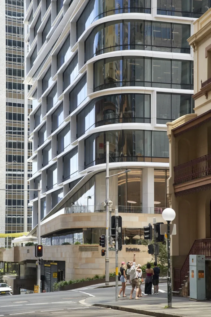 Pedestrians pointing at the curved glass facade of Quay Quarter Tower in Sydney