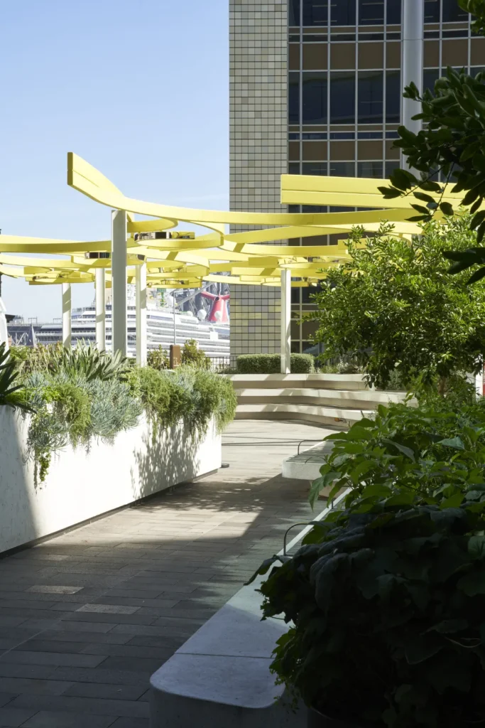 Yellow sculptural canopy with planted terraces at Quay Quarter Tower harbour bridge background