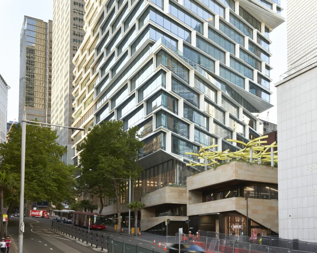 Quay Quarter Tower in Sydney seen from from street level, sandstone volumes, glass facade and yellow canopy sculpture by 3XN Architects and BVN Architecture