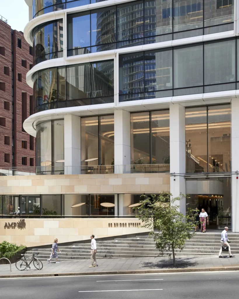 Pedestrians passing the curved glass facade of Quay Quarter Tower in Sydney